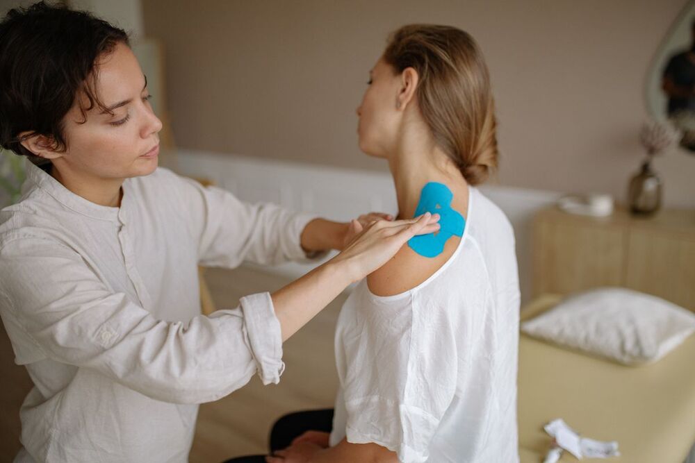 Physiotherapist applying tape to a patient's shoulder